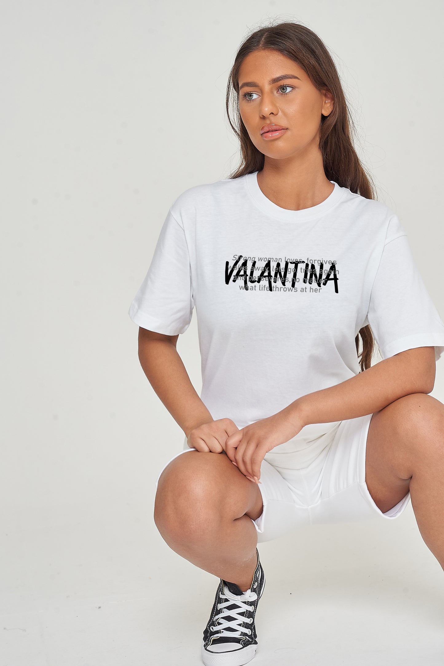 Woman wearing the white Strong Woman Oversized T-Shirt styled with casual bottoms, highlighting the empowering front graphic and comfortable fit.