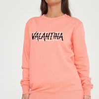 Woman wearing the coral Strong Woman Sweatshirt styled with casual bottoms, showcasing the empowering front graphic and comfortable fit.