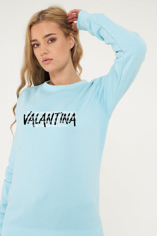 Woman wearing the turquoise Strong Woman Sweatshirt styled with casual bottoms, highlighting the empowering front print and comfortable fit.