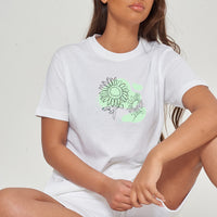 Woman wearing the white Sunflower Green Print Oversized T-Shirt styled with casual bottoms, showcasing the vibrant front floral graphic and comfortable fit.