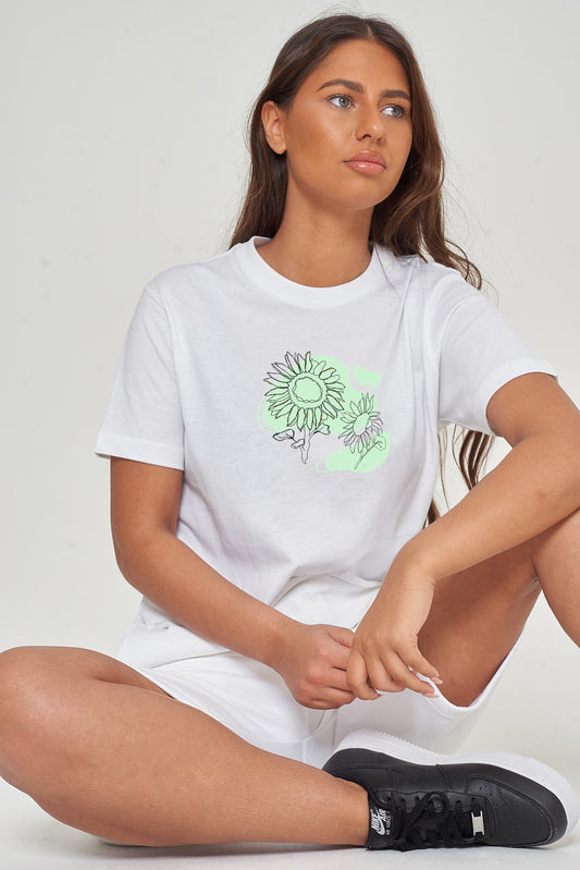 Woman wearing the white Sunflower Green Print Oversized T-Shirt styled with casual bottoms, showcasing the vibrant front floral graphic and comfortable fit.
