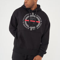 Male model front view wearing black Unseen Season One Oversized Hoodie with powerful graphic, paired with casual pants – oversized fit.