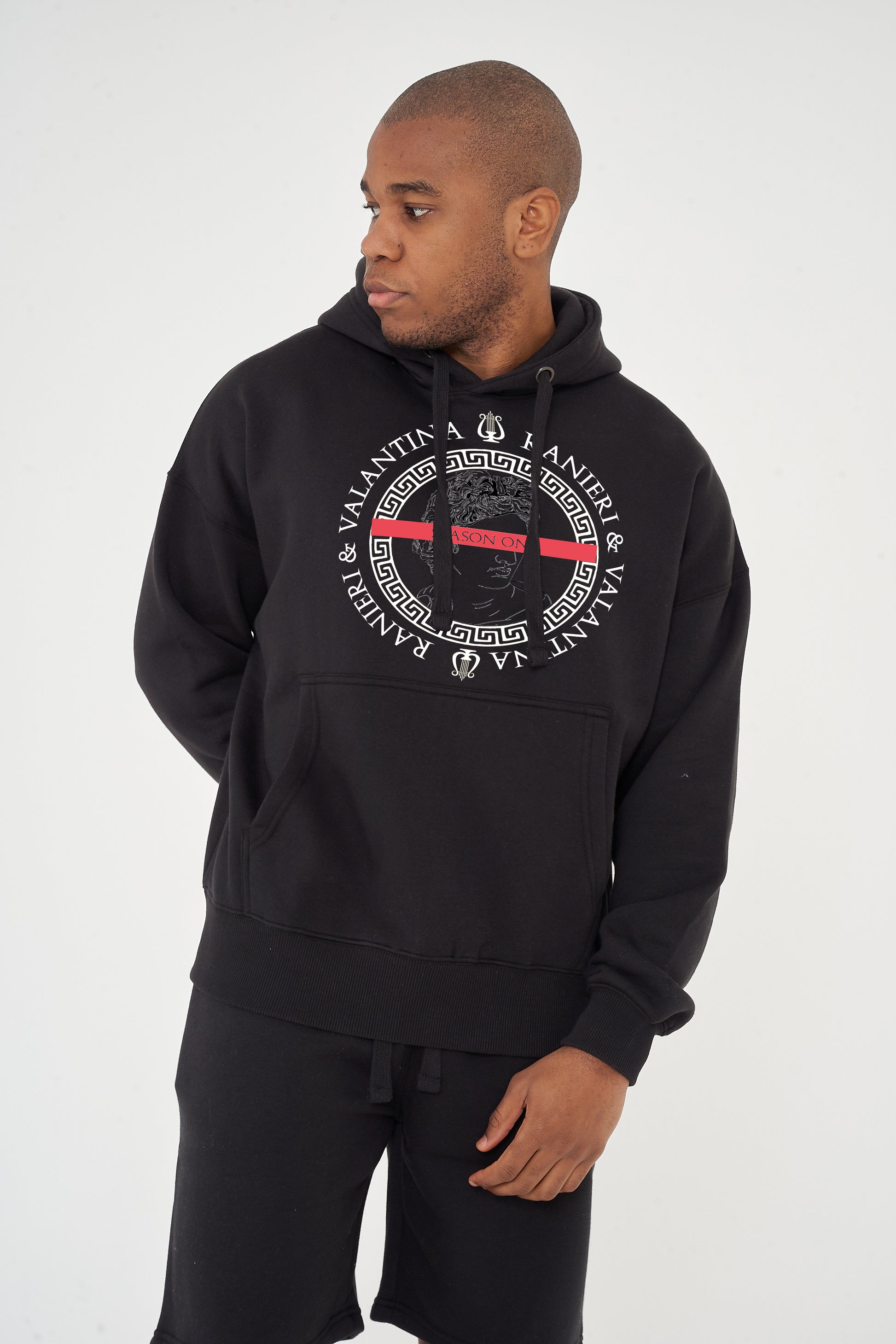 Male model front view wearing black Unseen Season One Oversized Hoodie with powerful graphic, paired with casual pants – oversized fit.