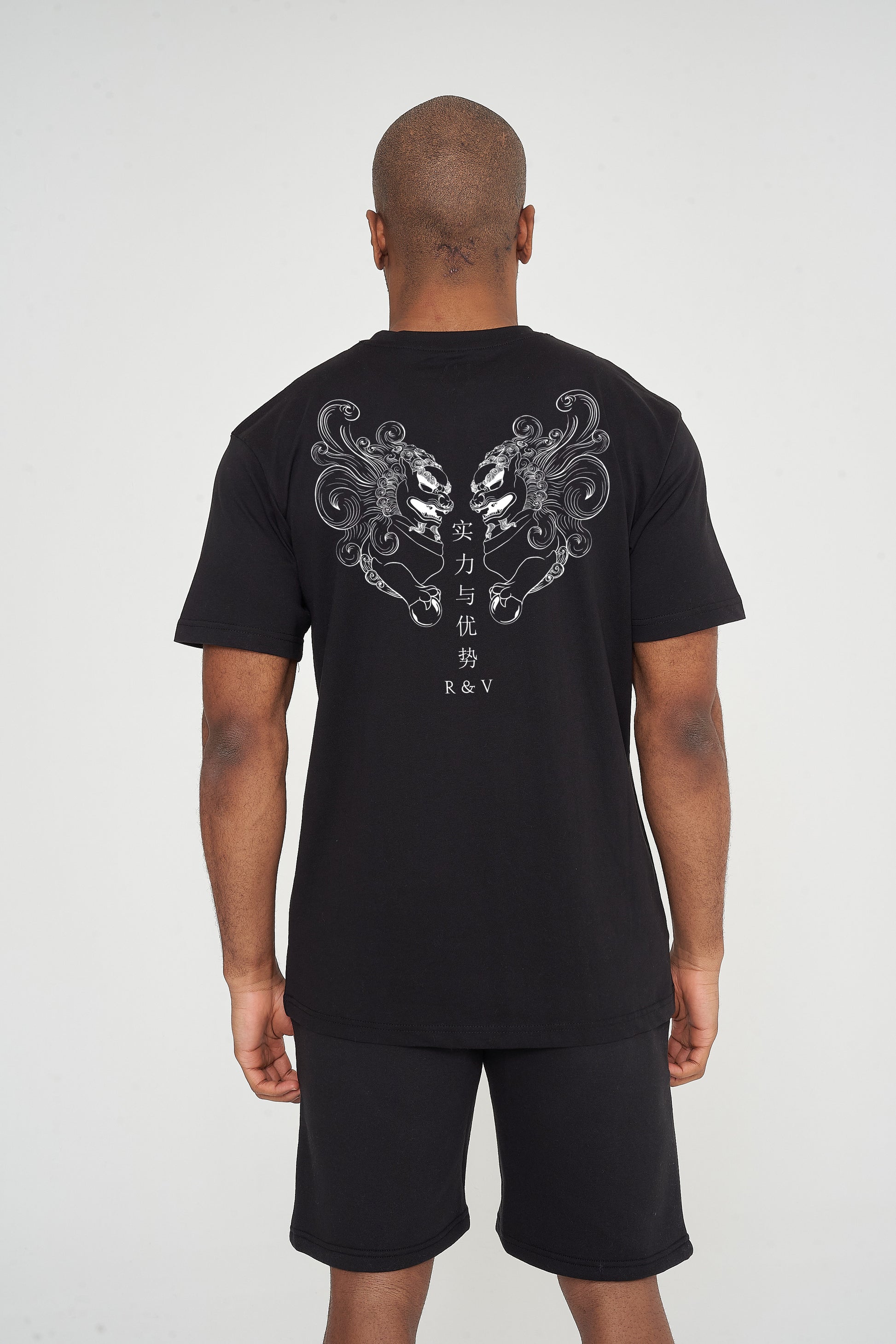  Man wearing the black Twin Lion Oversized T-Shirt styled with casual bottoms, showcasing the striking back graphic and comfortable oversized fit.