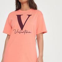 Woman wearing coral Valantina Signature Graphic T-Shirt styled with casual bottoms, highlighting the front signature print and comfortable silhouette.