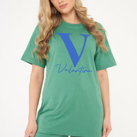 Woman wearing a green Valantina Signature Graphic T-Shirt styled with casual bottoms, highlighting the front signature print and comfortable silhouette.