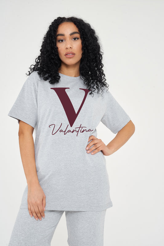 Woman wearing the grey Valantina Signature Graphic T-Shirt styled with casual bottoms, highlighting the front signature print and comfortable fit.