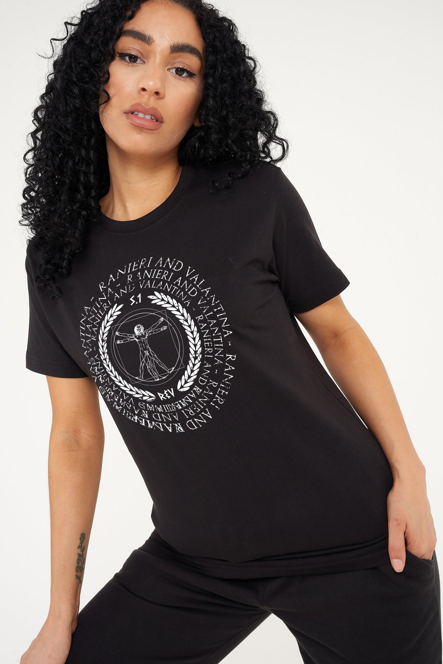 Woman wearing the black Vitruvian T-Shirt styled with casual denim bottoms, highlighting the front artistic print and comfortable oversized fit.