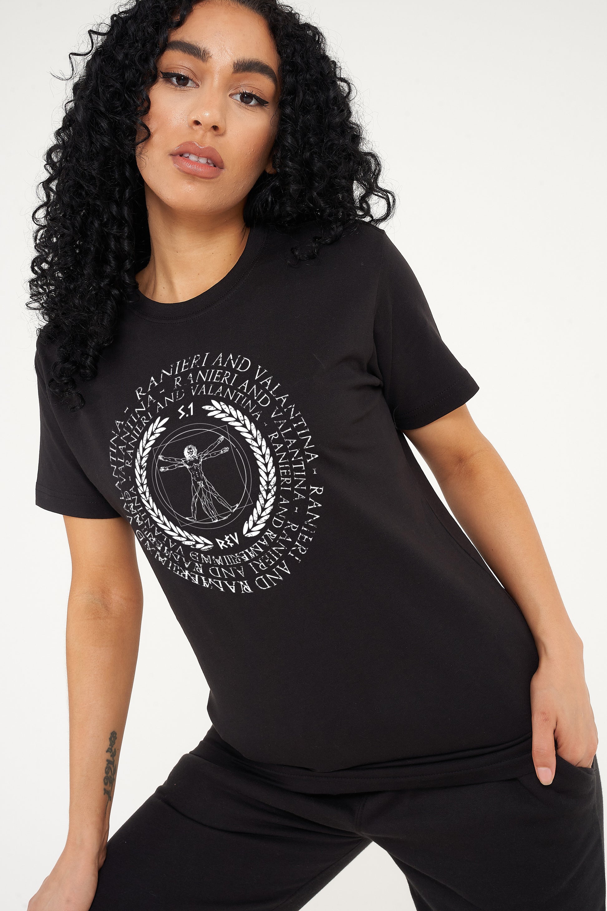 Woman wearing the black Vitruvian T-Shirt styled with casual denim bottoms, highlighting the front artistic print and comfortable oversized fit.