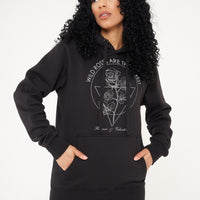 Woman wearing black Wild Roses sweatshirt and black trousers, showcasing relaxed UK streetwear style.
