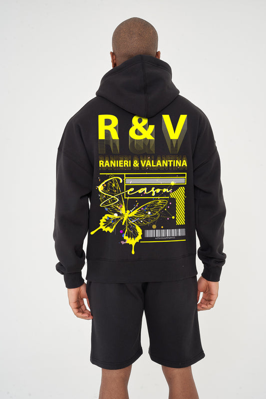 Rear view of male model wearing black oversized hoodie with striking yellow butterfly graphic and R&V print – oversized fit.